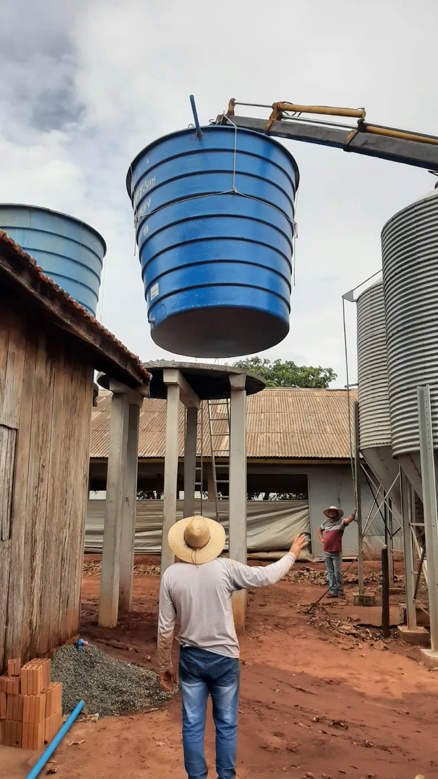 Reservatório sendo instalado em granja com silos ao lado