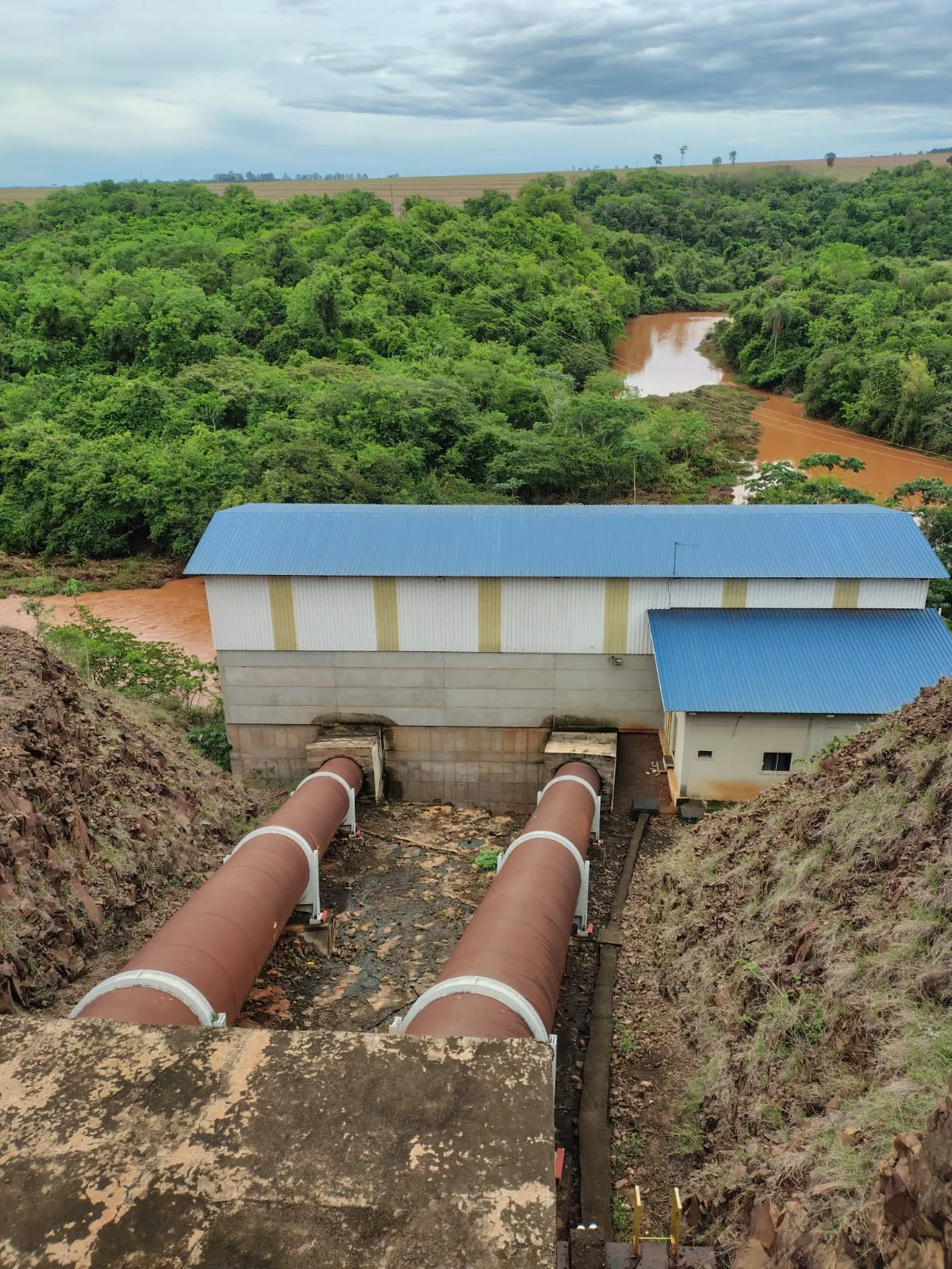 Estrutura industrial com tubulações de grande porte próximas ao rio